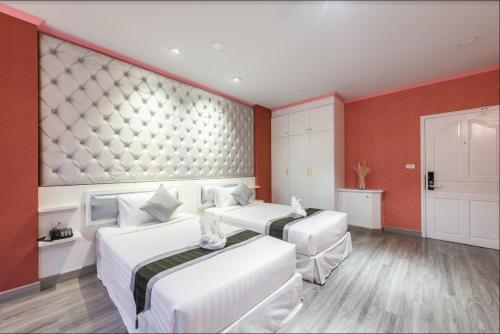 two beds in a room with red walls at Napheera Royal Tel in Ban Khlong Bang Krathiam