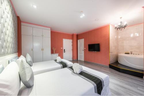 a bedroom with two beds and a tub and a television at Napheera Royal Tel in Ban Khlong Bang Krathiam