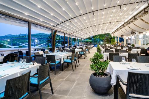a restaurant with white tables and chairs and windows at Romantique Veles Hotel in Veles