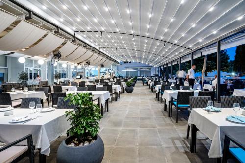 a restaurant with white tables and chairs and people in the background at Romantique Veles Hotel in Veles