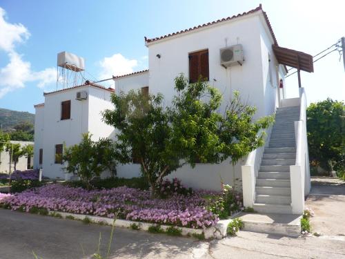 a white house with a staircase and flowers at Studios Calvinos in Marathokampos