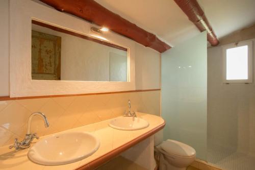 a bathroom with two sinks and a toilet and a mirror at Casa Los Arcos at Masia Nur Sitges, Adults only in Canyelles