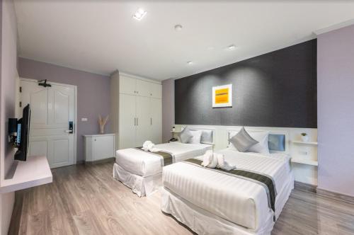 a bedroom with two beds and a flat screen tv at Napheera Royal Tel in Ban Khlong Bang Krathiam