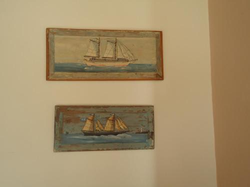 two framed paintings of a sailboat on a wall at STONE ROSE VILLA in Agios Ioannis