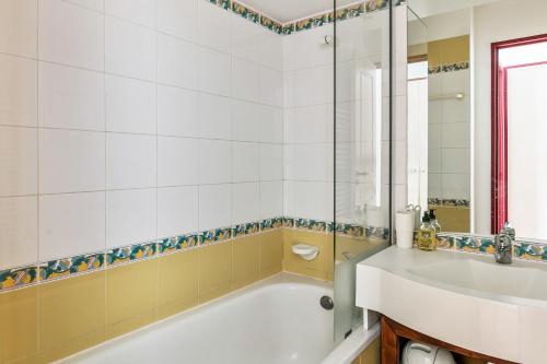 une salle de bain avec une baignoire et un lavabo dans l'établissement Residence Le Mont Soleil - maeva Home, à Plagne Villages