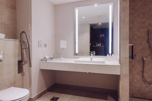 a bathroom with a sink and a toilet and a mirror at Radisson Blu Hotel, Nairobi Upper Hill in Nairobi