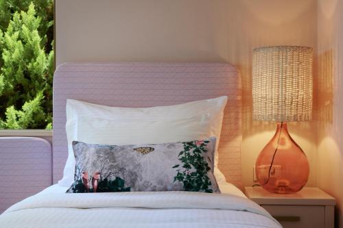 a bed with a pillow and a lamp next to a window at Artblue Villas in Tsoukaladhes