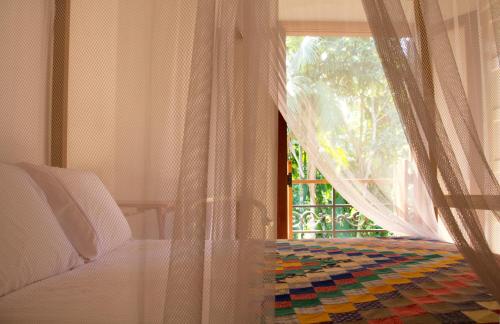 a bedroom with a bed and a window with curtains at Estalagem Camburi in Camburi