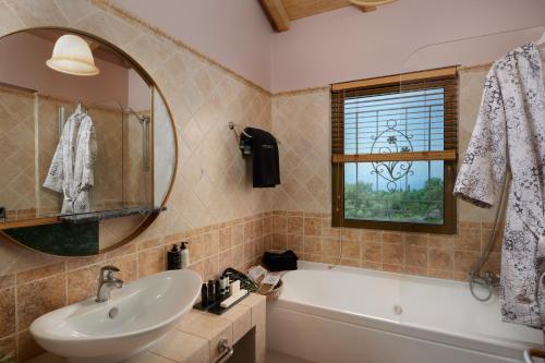 a bathroom with a sink and a tub and a mirror at Artblue Villas in Tsoukaladhes