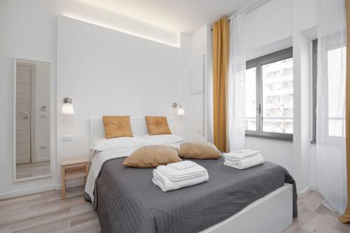 a white bedroom with a bed with two towels on it at De Guestibus in Rome