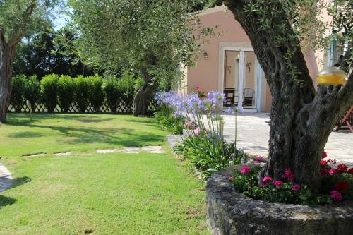 a garden with purple and pink flowers and a tree at STONE ROSE VILLA in Agios Ioannis