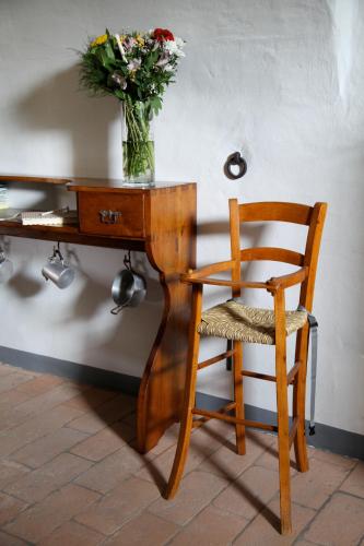 a wooden desk with a vase of flowers and a chair at A Casa Di Mìnola in Roe