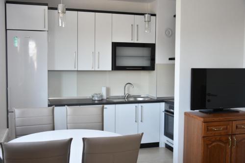 a kitchen with white cabinets and a table and a tv at Relax Teslić in Teslić