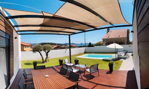 a patio with a wooden table and chairs and a pool at Chalet Mia Sear Areas in Sanxenxo