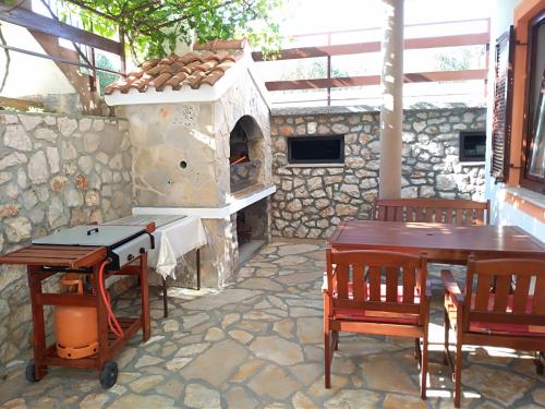 un patio con horno de pizza, mesas y sillas en Apartments Boris, en Jezera