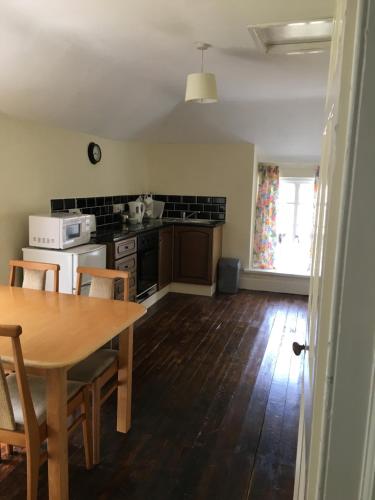 a kitchen with a wooden table and a dining room at Ballydivity House in Ballymoney