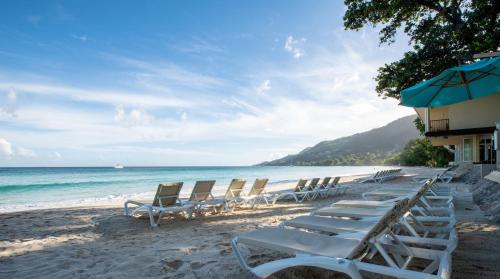 a beach area with chairs, tables and umbrellas at Coral Strand Smart Choice in Beau Vallon