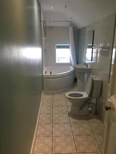 a bathroom with a tub and a toilet and a sink at Ballydivity House in Ballymoney