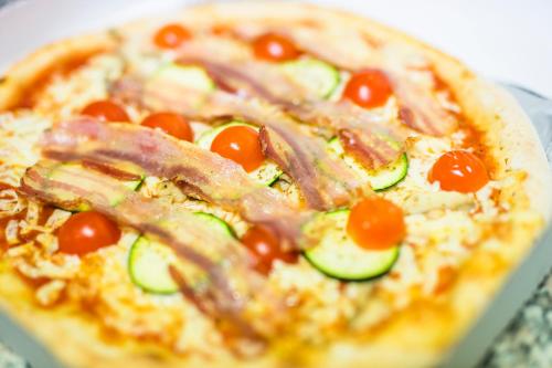 a pizza with ham and vegetables on a table at Guesthouse Urša in Preddvor
