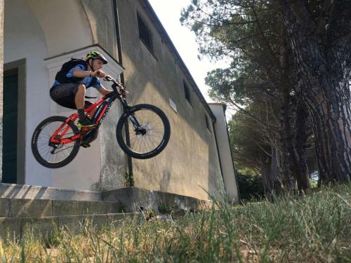 Una persona che fa un trucco con una bici contro un muro di La Cantina Del Sole a Riccò del Golfo di Spezia