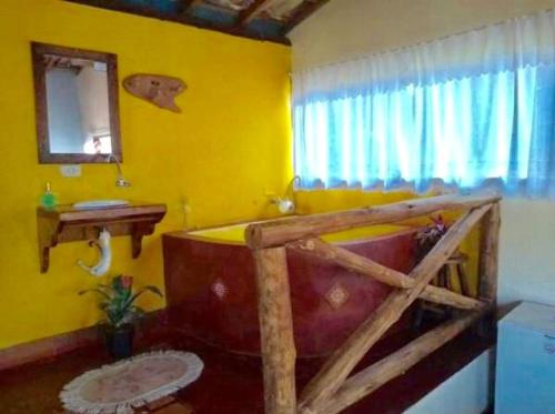 a bathroom with a large tub in a yellow room at Pousada Recanto da Siriema in Monte Alegre do Sul
