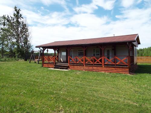 a small cabin in a field of grass with a playground at Domki przy Puszczy Białowieskiej in Dubicze Cerkiewne