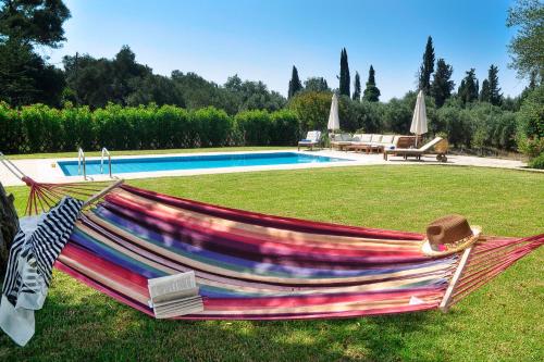 a hammock sitting in the grass next to a pool at STONE ROSE VILLA in Agios Ioannis
