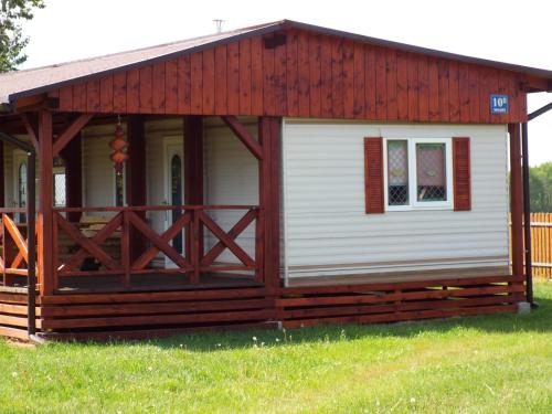 eine Hütte mit rotem Dach und einer Veranda in der Unterkunft Domki przy Puszczy Białowieskiej in Dubicze Cerkiewne