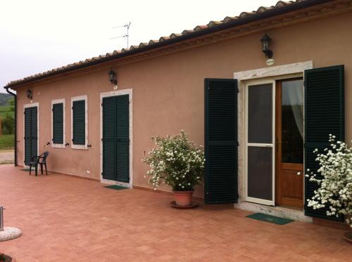 a house with green shutters and a patio at Piane Del Bagno in Saturnia