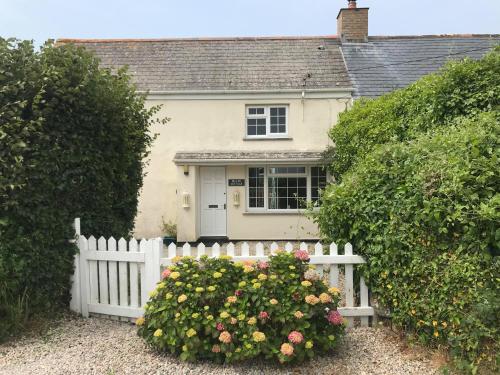 a white fence in front of a house with flowers at Buller Cottage in Cornwall in Newquay