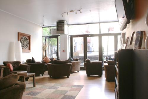 ein Wohnzimmer mit Sofas, Stühlen und Fenstern in der Unterkunft Off SoHo Suites Hotel in New York