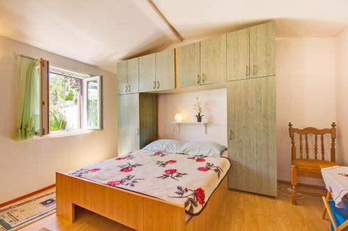 a bedroom with a bed and a chair and a window at House Verica in Veli Lošinj