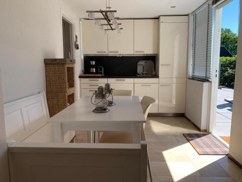 a kitchen with white cabinets and a white table at Vakantiebungalow Mee naar Ouddorp aan zee in Ouddorp
