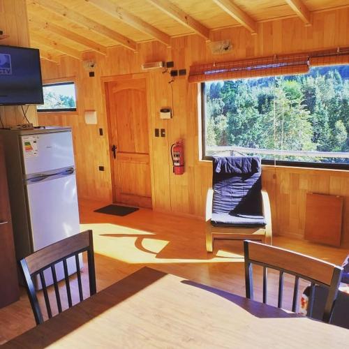 a kitchen with a refrigerator and a table in a room at Cabañas Latitud 41 Sur in Quillaipe