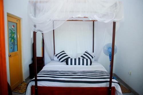 a bedroom with a canopy bed with two striped pillows at Welcome Homestay in Ella