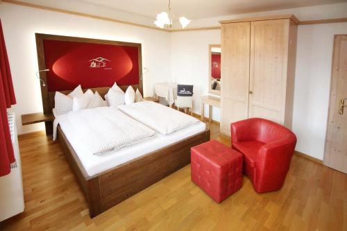 a bedroom with a large bed and a red chair at Schätzlhof OHG in Ruderting