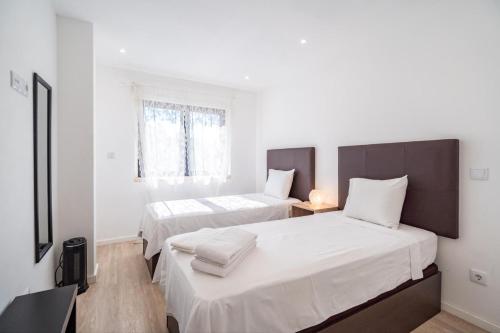 two beds in a room with white walls at Akicity Lisboa Pearl II in Lisbon