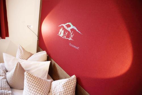 a bedroom with a red wall and a bed with pillows at Schätzlhof OHG in Ruderting