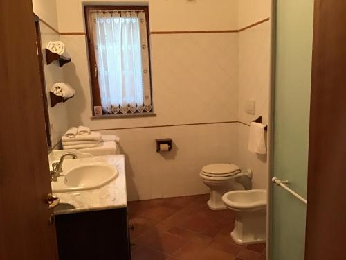 a bathroom with a sink and a toilet and a window at casa Anna De Croy in Magliano in Toscana