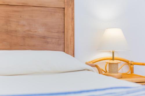 Un dormitorio con una cama y una lámpara sobre una mesa. en Four Rooms, en Carloforte