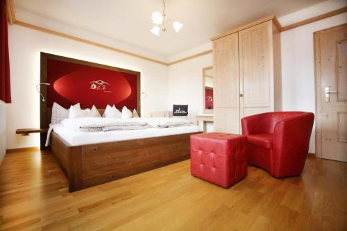 a bedroom with a bed and a red chair at Schätzlhof OHG in Ruderting