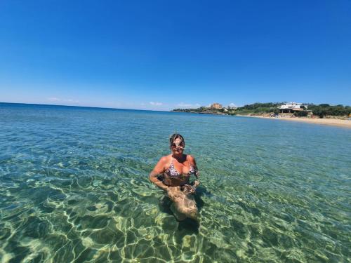 a man standing in the water with a turtle at Resort ' Njulella in Migliarello