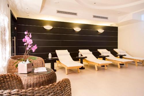 a waiting room with chairs and tables and a black wall at AHR Baja Hotel & Spa Cannigione in Cannigione
