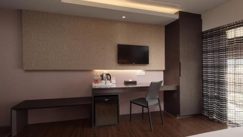 a hotel room with a desk with a television on the wall at Fine Hotel in Kaohsiung