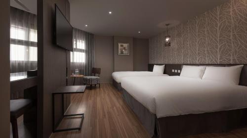 a hotel room with two beds and a flat screen tv at Fine Hotel in Kaohsiung