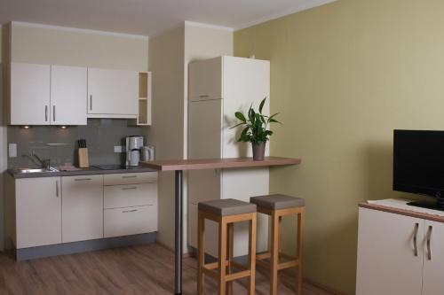 a kitchen with white cabinets and a table and stools at Hölbinger Alm - Apartments in Anger