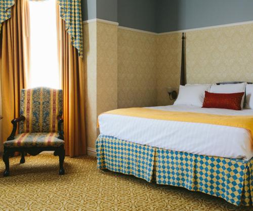 a bedroom with a bed and a chair and a window at Carleton of Oak Park in Oak Park