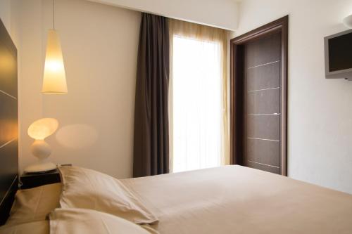 a bedroom with a white bed and a window at AHR Baja Hotel & Spa Cannigione in Cannigione