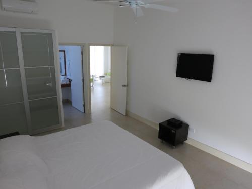 a bedroom with a white bed and a flat screen tv at Tamarindo in San Andrés