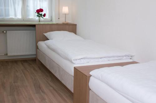 two beds in a room with a window and a vase with a red flower at Hölbinger Alm - Apartments in Anger